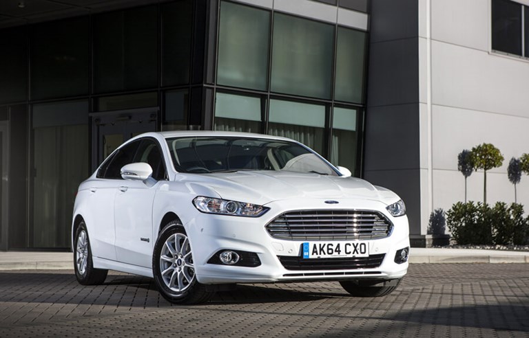 Large, spacious, white Ford rental car parked in front of a modern, office building.